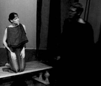 B&W photo of a woman kneeling and staring at a soldier. 